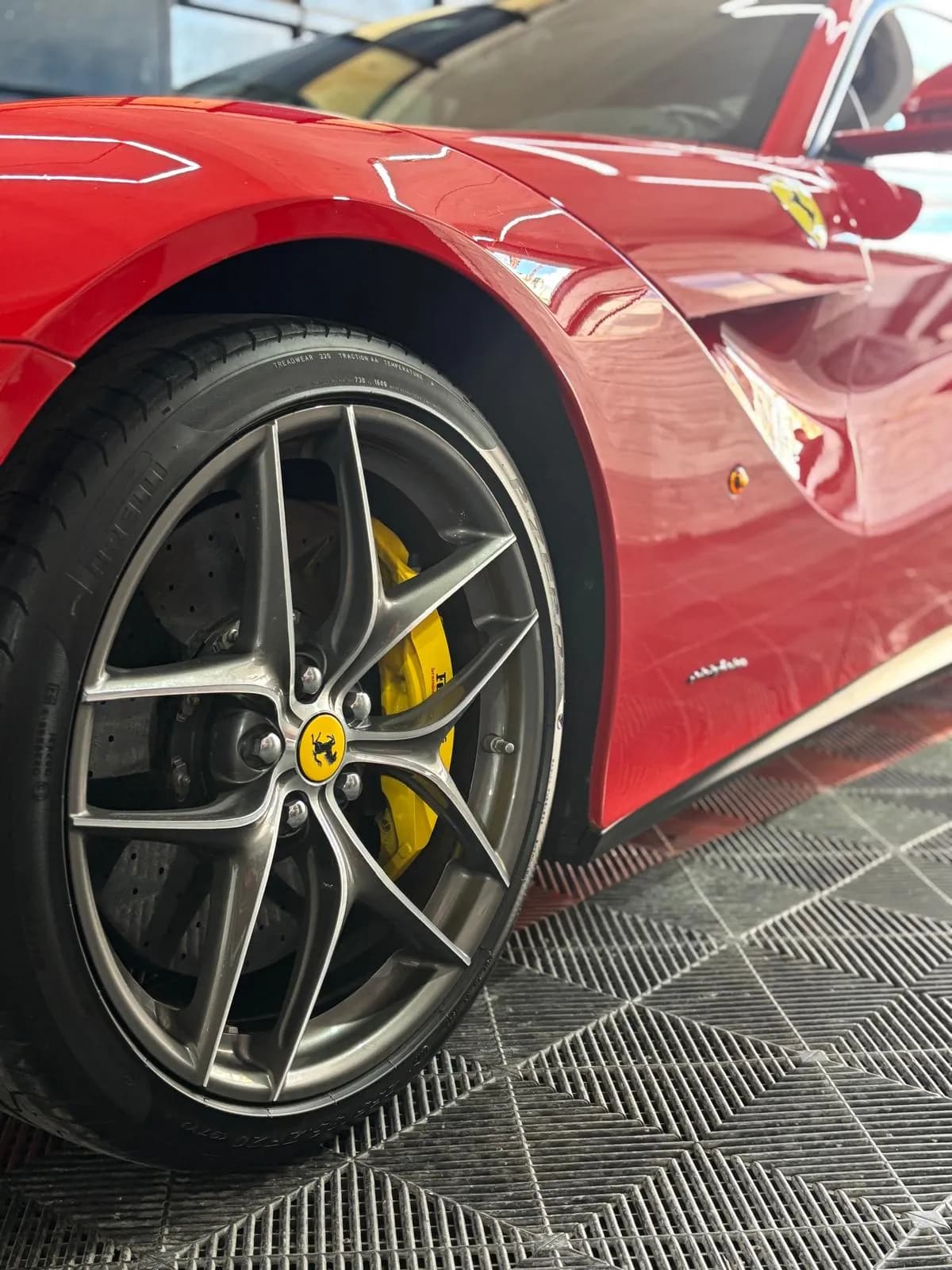 Lateral de un deportivo rojo con la llanta y la pinza de freno amarilla, con los reflejos limpios sobre la chapa
