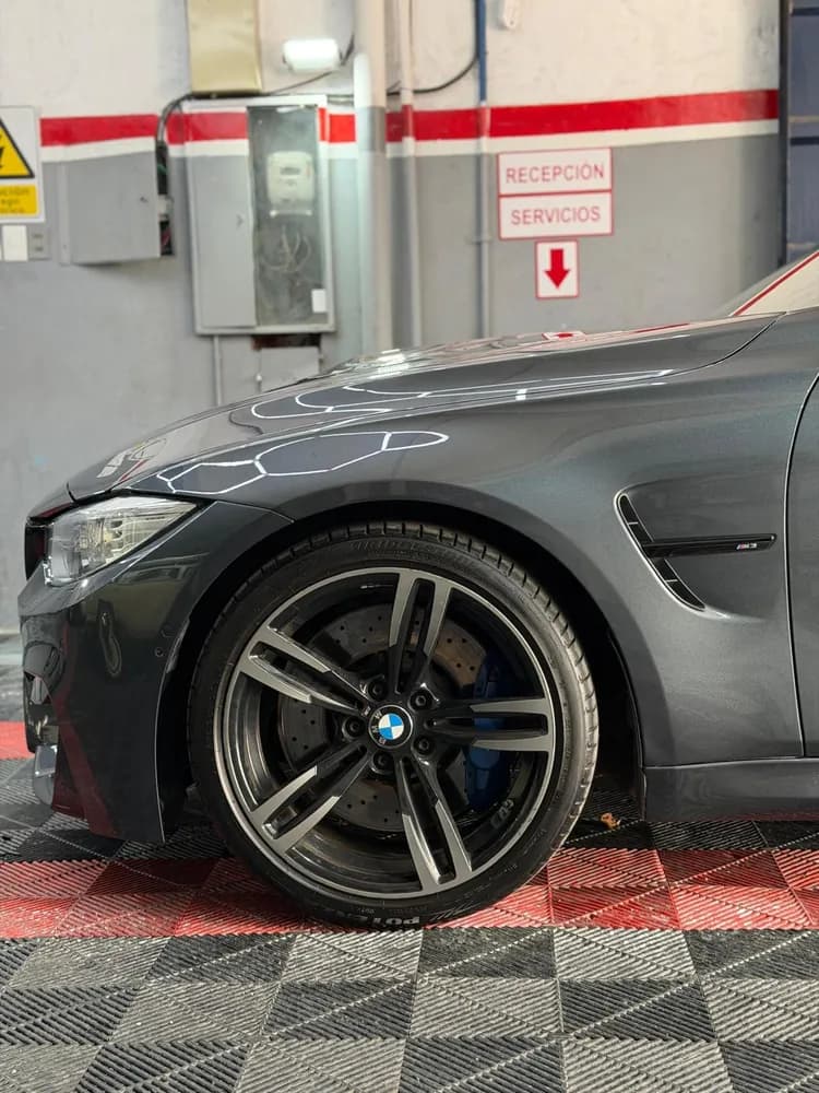 Lateral delantero de un auto gris oscuro con llanta deportiva y pinza de freno azul